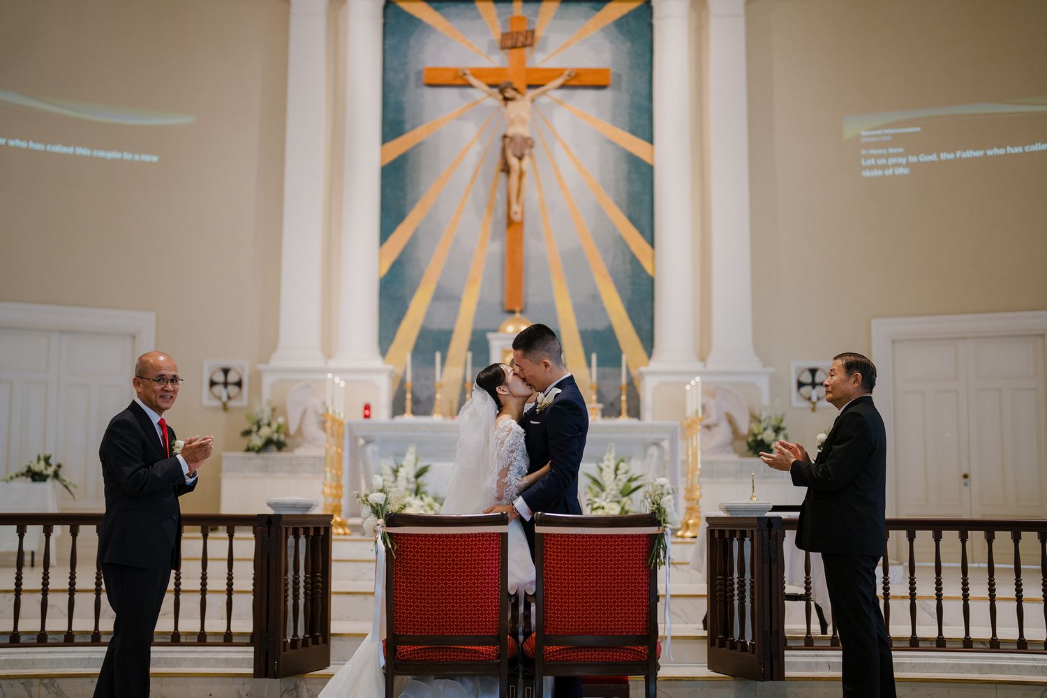 Wedding ceremony in progress at an ornate church altar with golden sunburst design and crucifix.