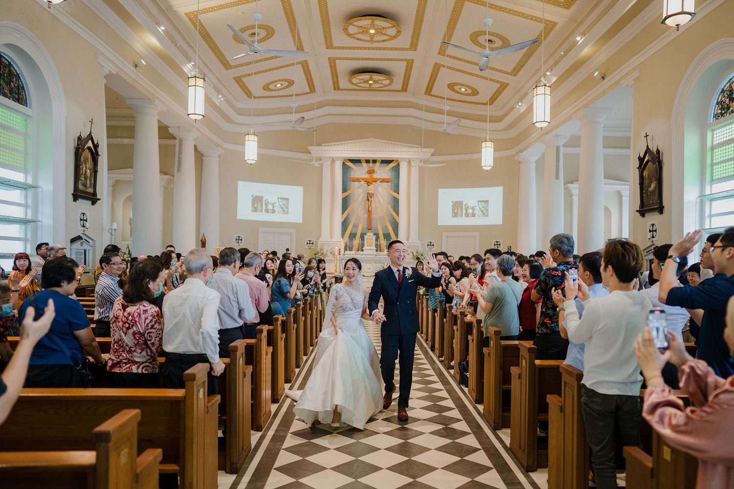 Elegant church sanctuary with wooden pews and a black and white checkered floor during a wedding ceremony.