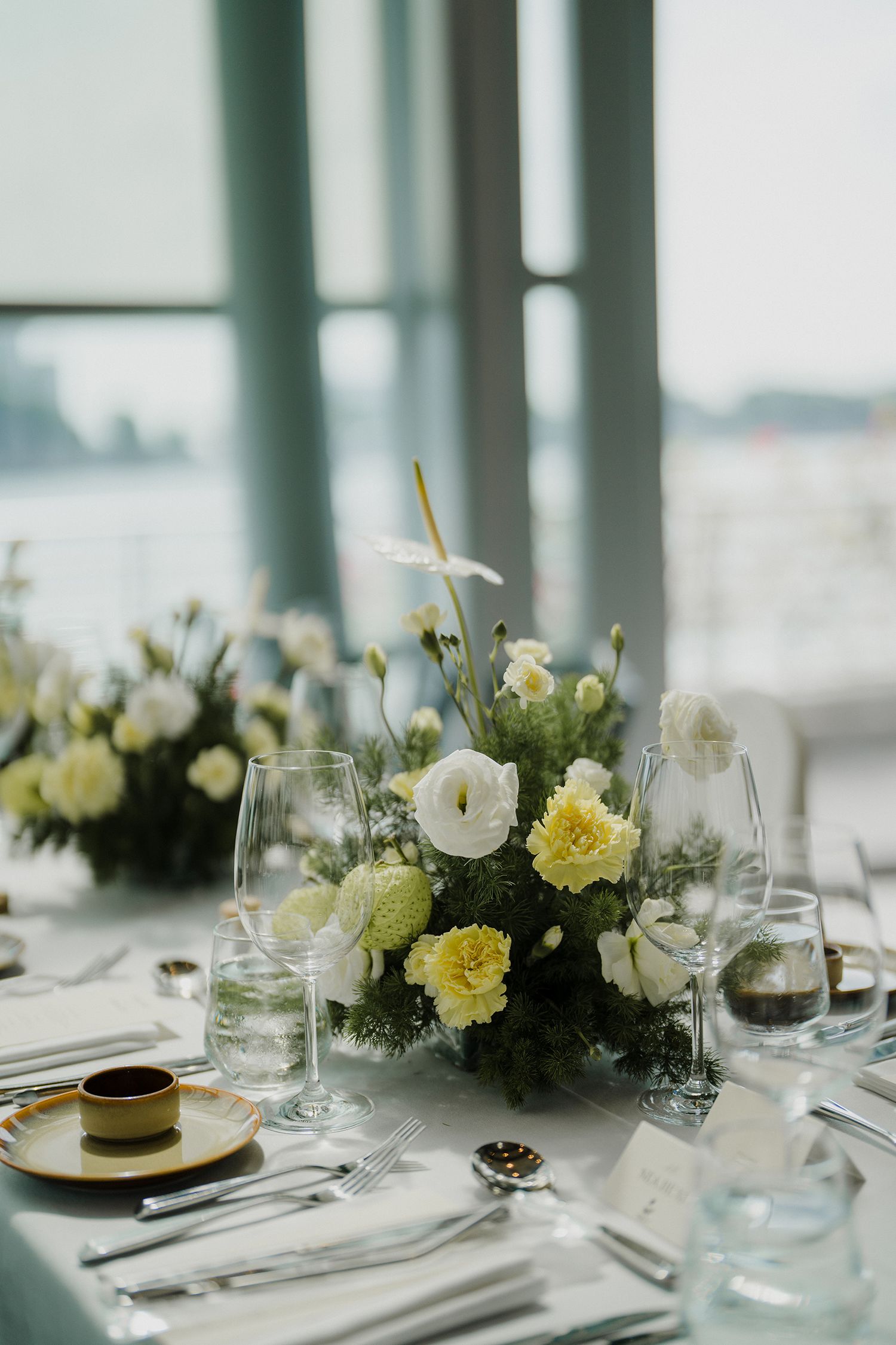 White and yellow floral centerpieces on elegant wedding reception tables.