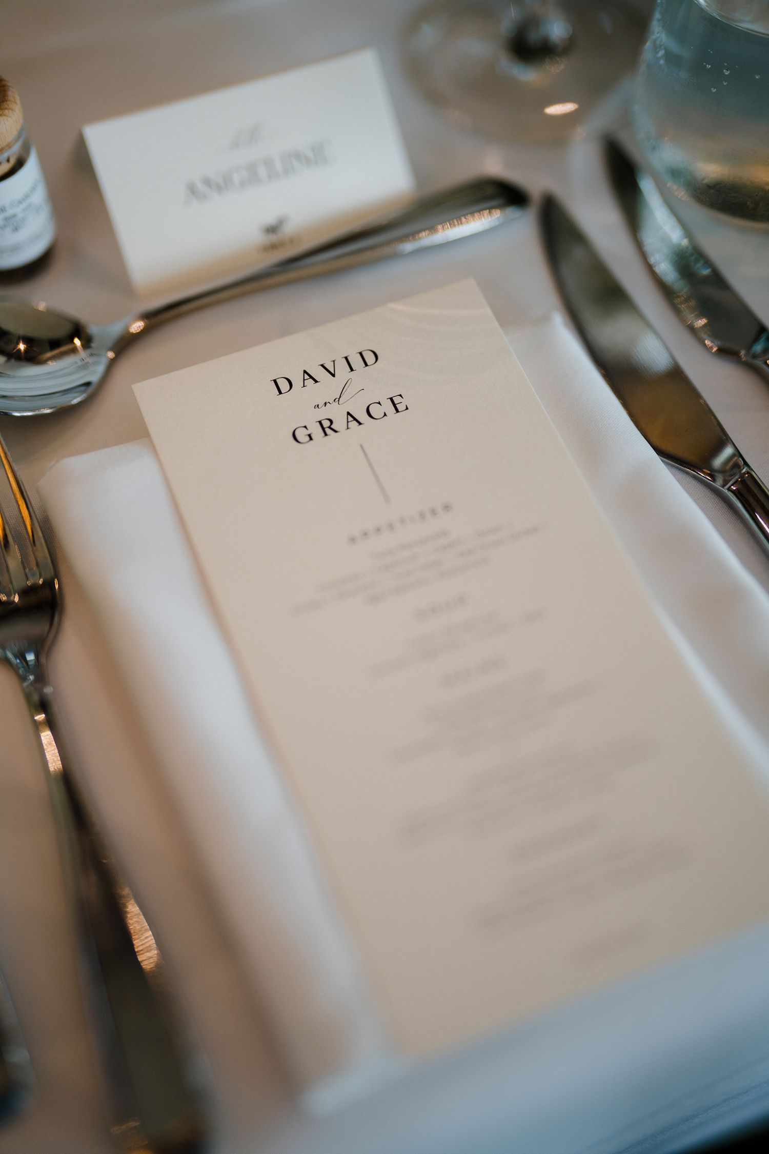 Wedding place settings with personalized menus on white tablecloths.
