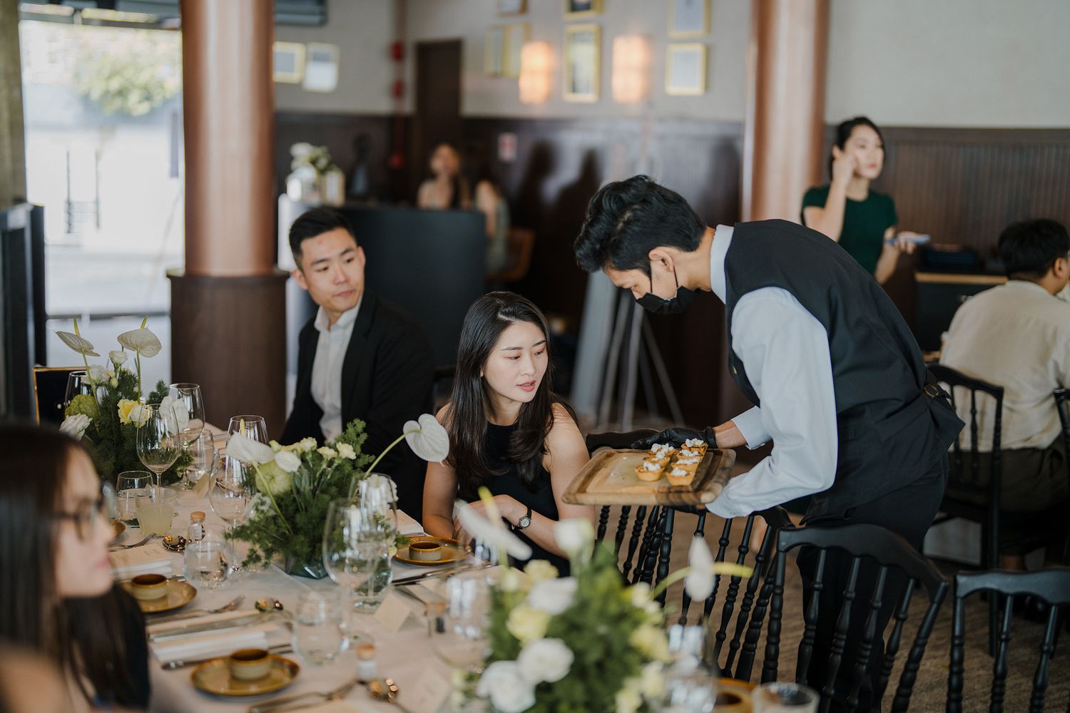 Elegant wedding reception dining setup with guests seated at tables.