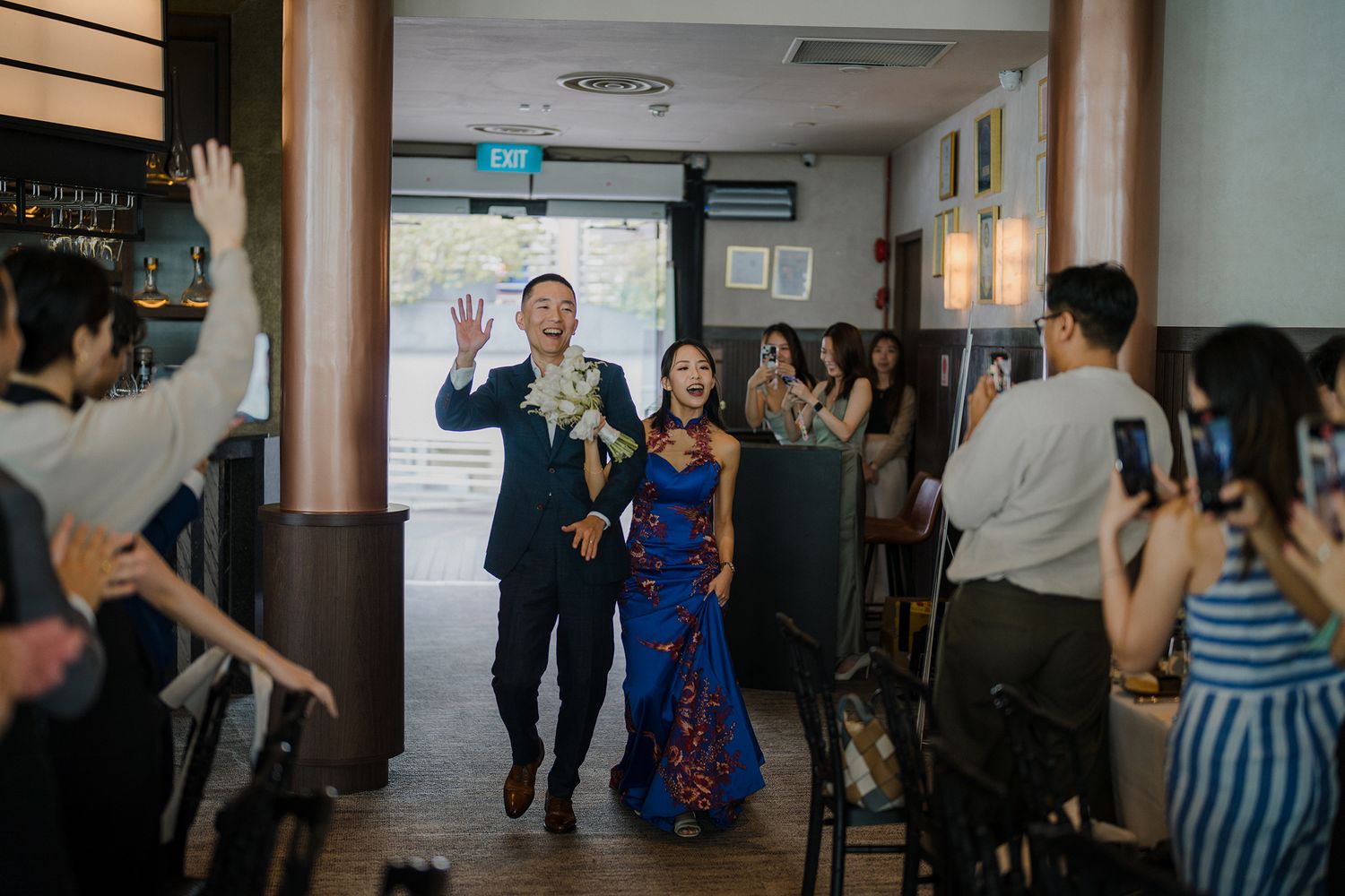 Wedding guests dancing and celebrating in a dimly lit indoor space.