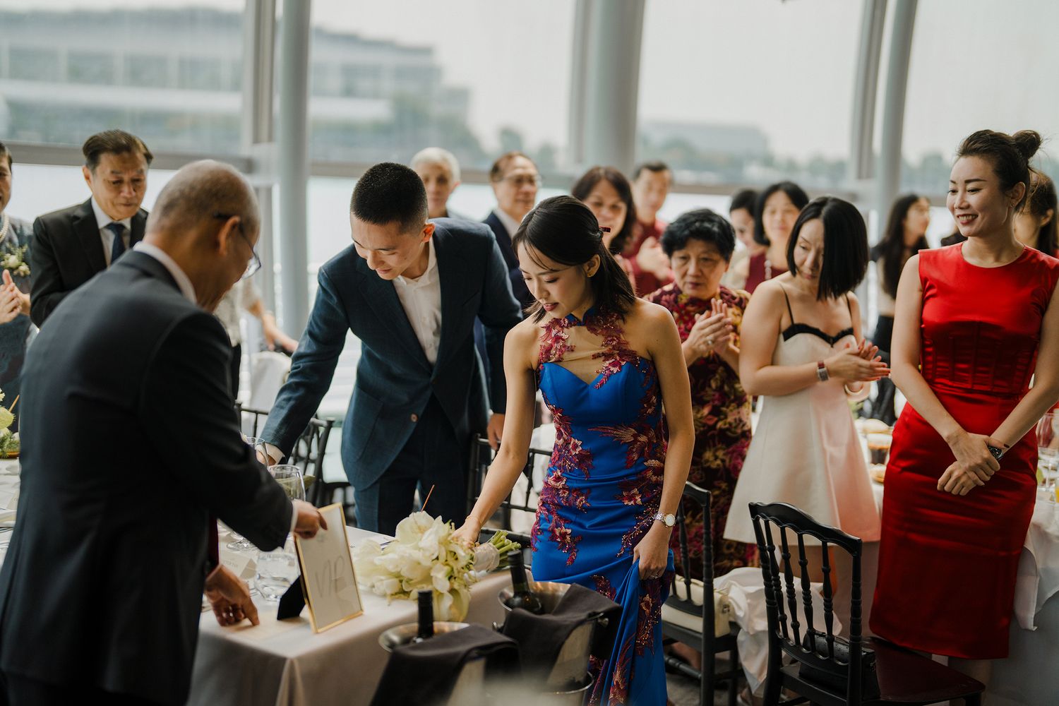 Wedding guests mingling at formal reception with elegant decor and natural lighting.