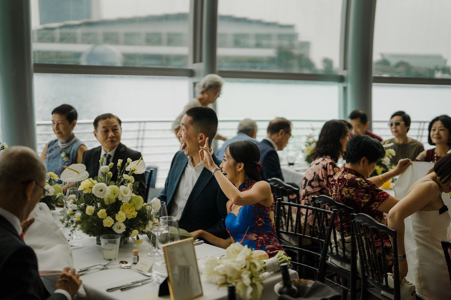 Modern wedding venue with panoramic windows and formal table settings decorated with white flowers.