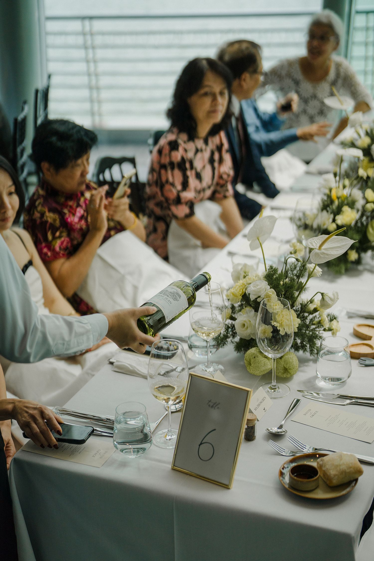 Elegant table settings with numbered cards, white flowers, and formal place settings at a wedding reception.