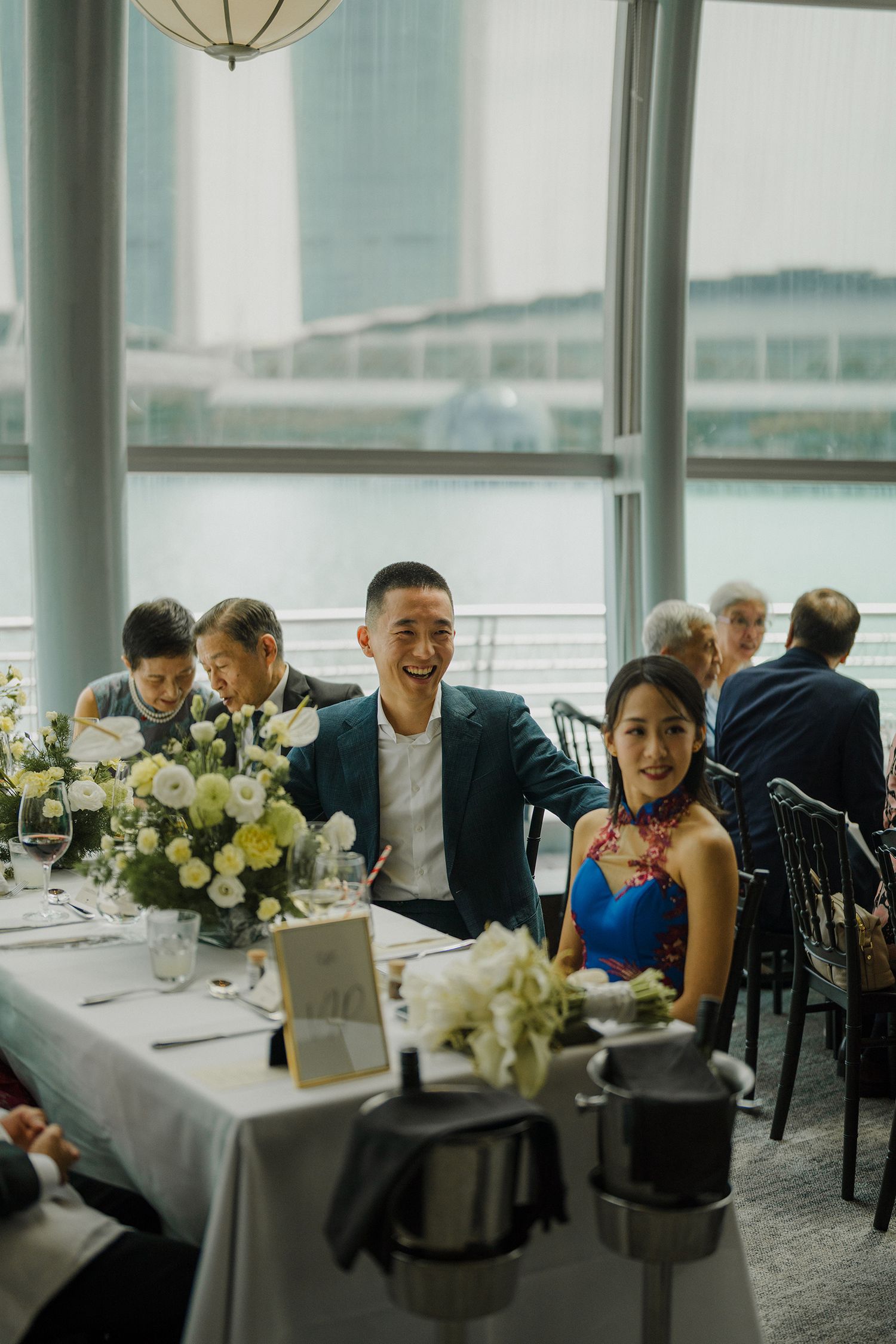 Modern reception venue with floor-to-ceiling windows overlooking city views and elegant table settings.