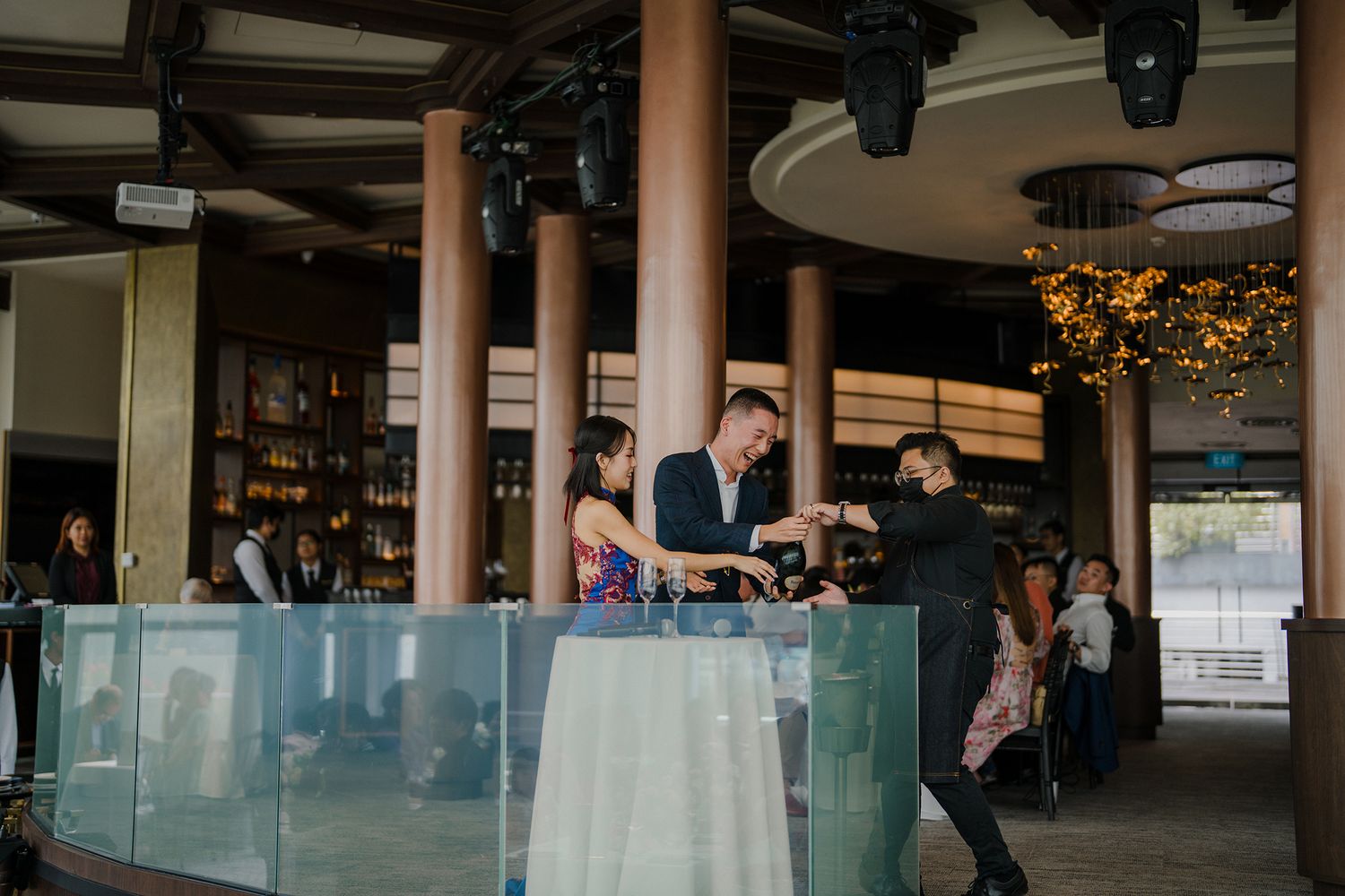 Modern restaurant venue with glass railings and wooden columns during a special event.