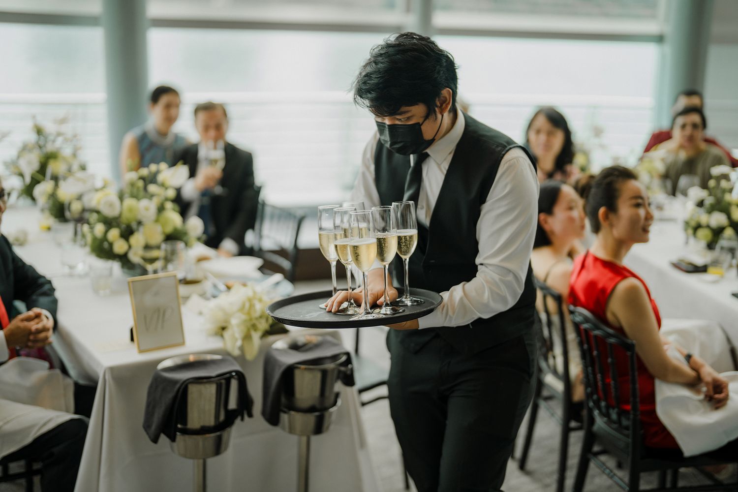 Server carrying champagne glasses on a tray during an elegant indoor event.