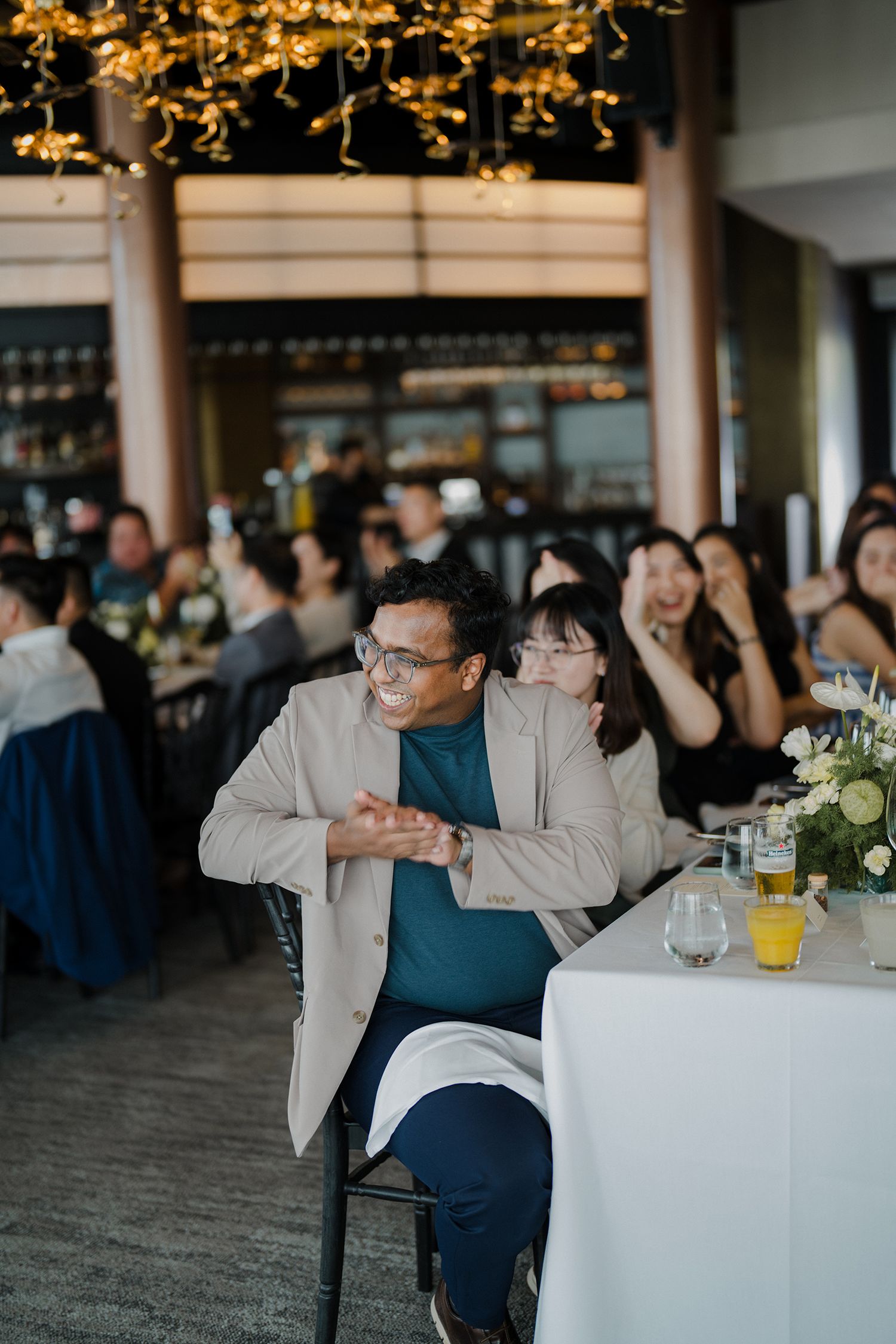 Guests seated at an elegant reception dinner with floral centerpieces and warm lighting in a modern restaurant venue.