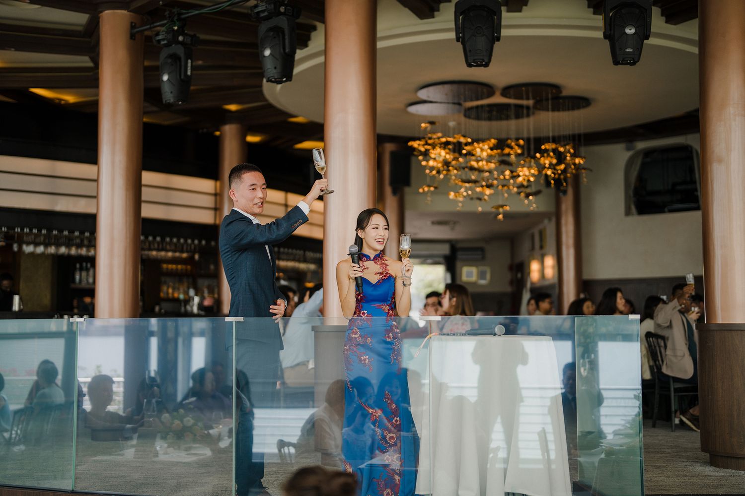 Wedding reception space features glass balustrades and decorative lighting.