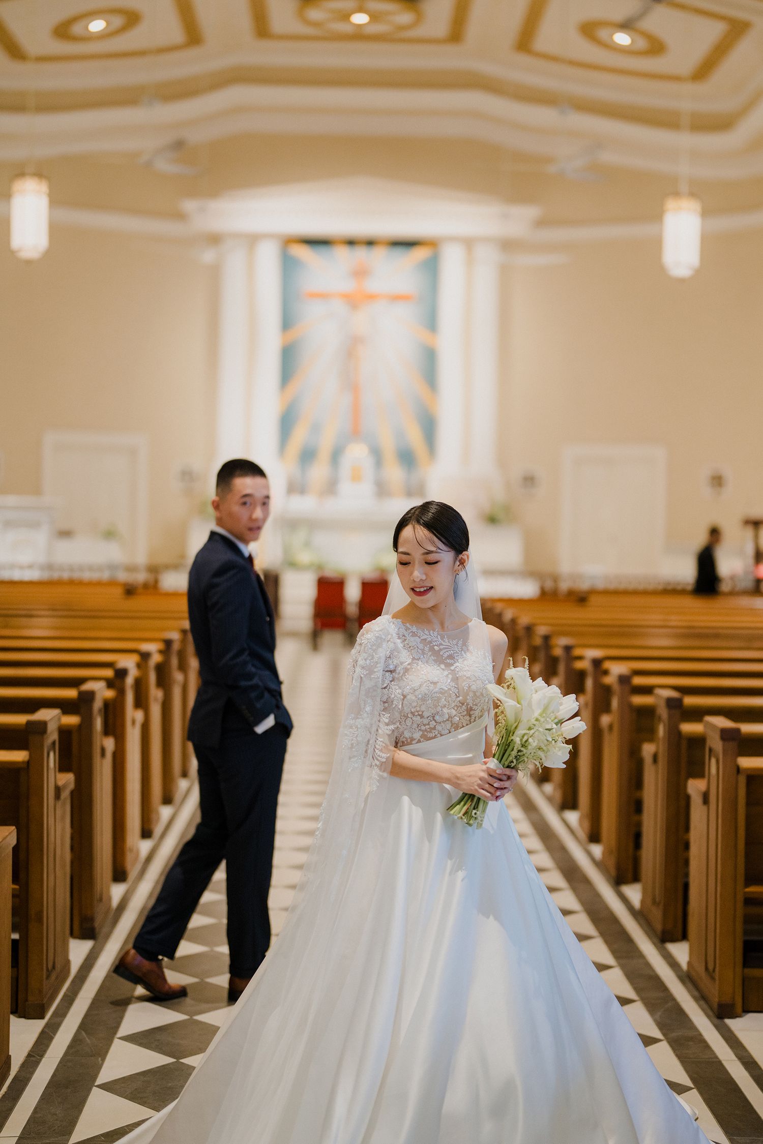 Wedding ceremony in traditional church with ornate ceiling and wooden pews.