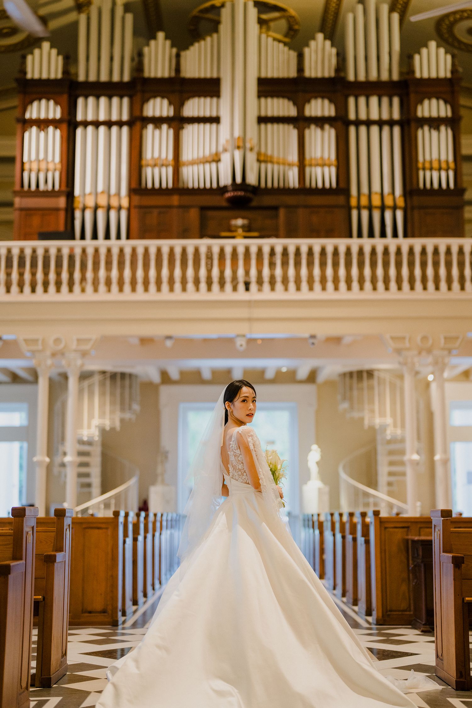 Church interior featuring grand pipe organ and elegant white wedding dress.