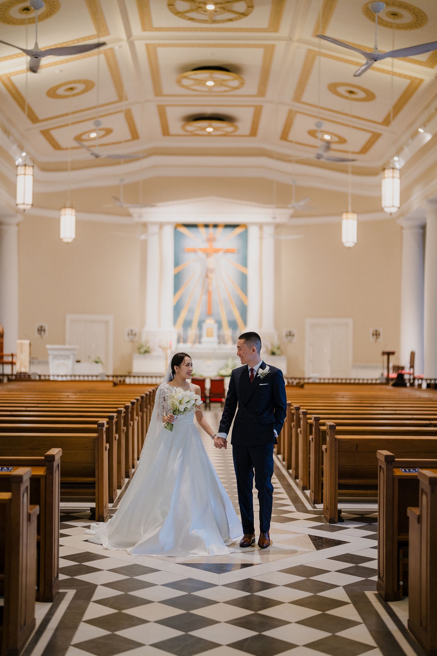 Wedding couple photographed in church with dramatic checkered floor and decorative ceiling.