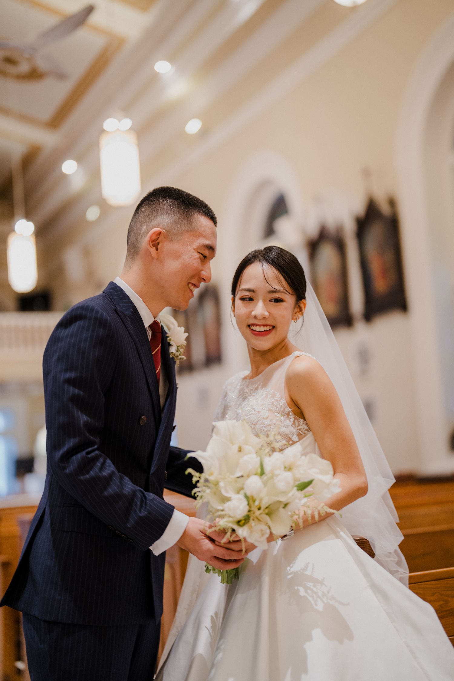 Couple shares intimate moment during wedding photos in church aisle.