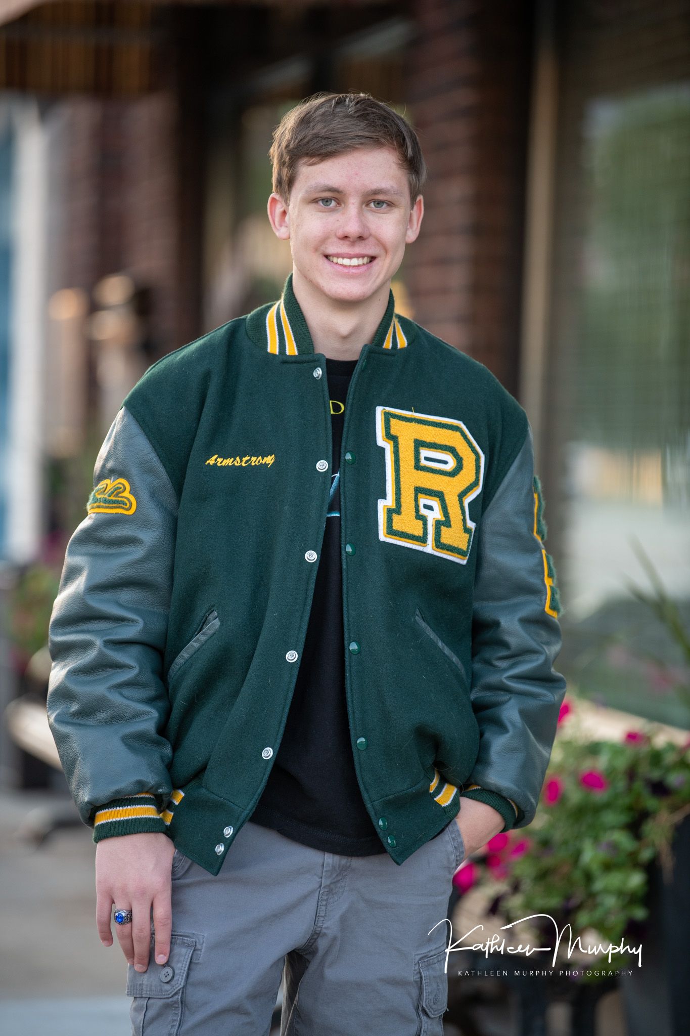 Athletic portrait wearing a green and gold varsity letterman jacket with 'R' patch.