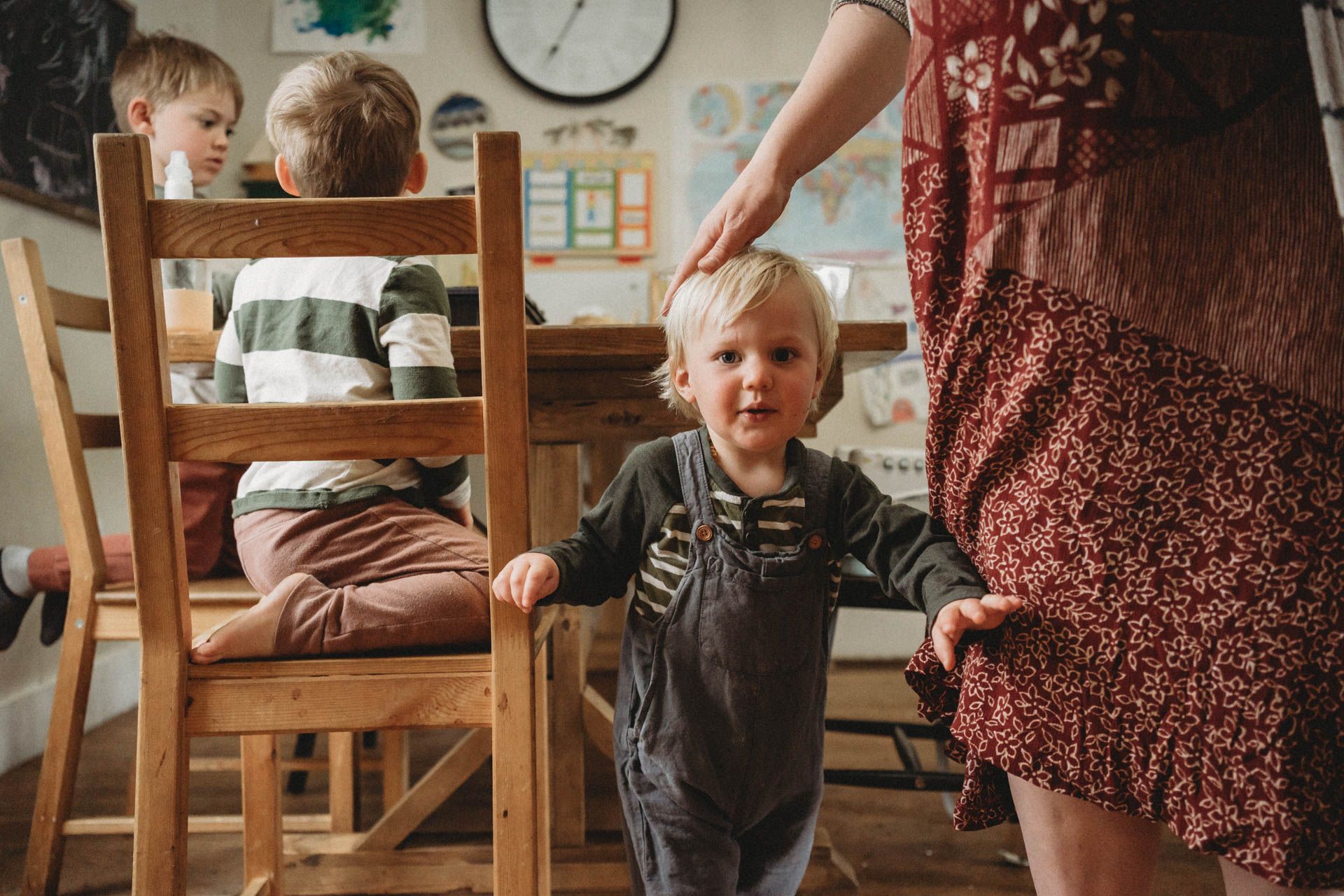 A cozy indoor family scene with wooden chairs and a floral dress in warm lighting.