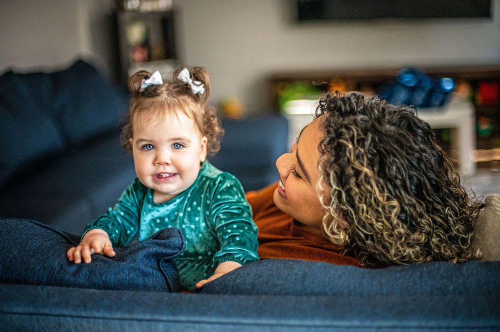Intimate candid moment of family interaction on blue couch in living room setting.