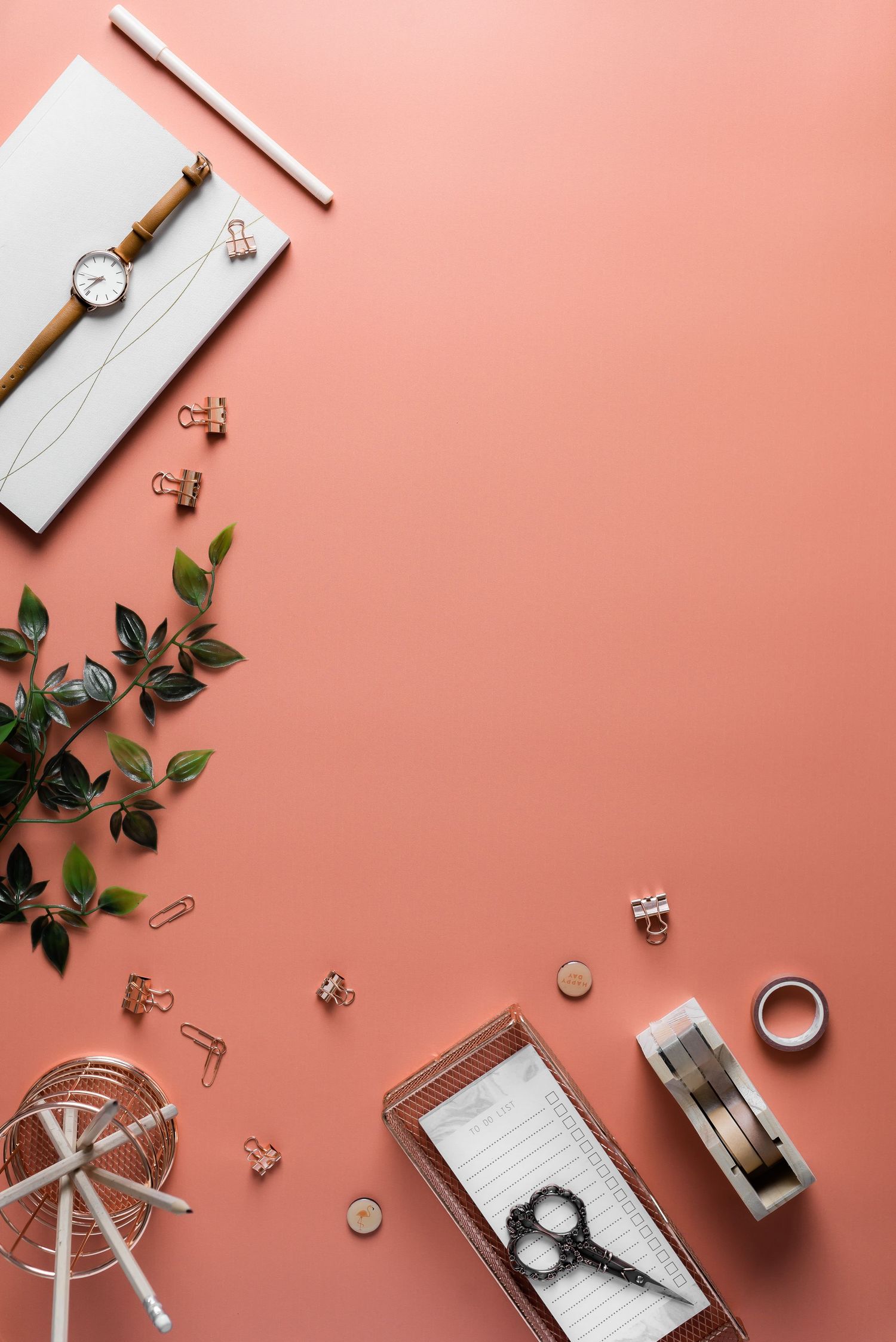 flatlay on a red backdrop with negative space for text, bordered with green plants and office stationery