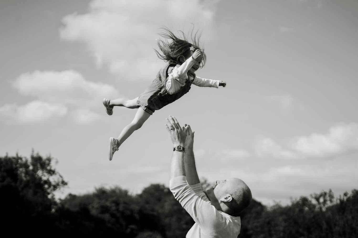 Black and white photo of playful moment with child being tossed in the air.