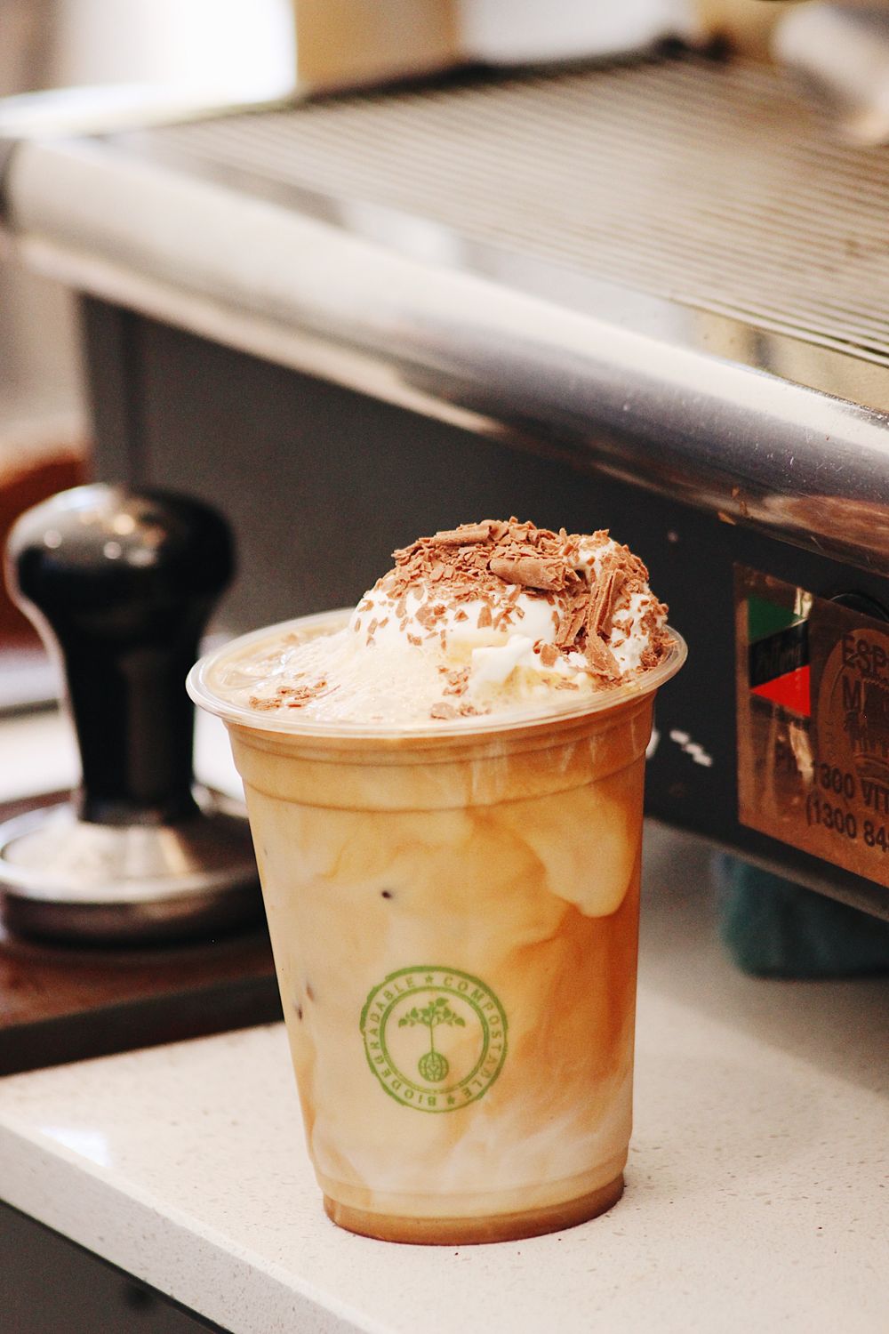 Creamy coffee drinks topped with cocoa powder in branded plastic cups.