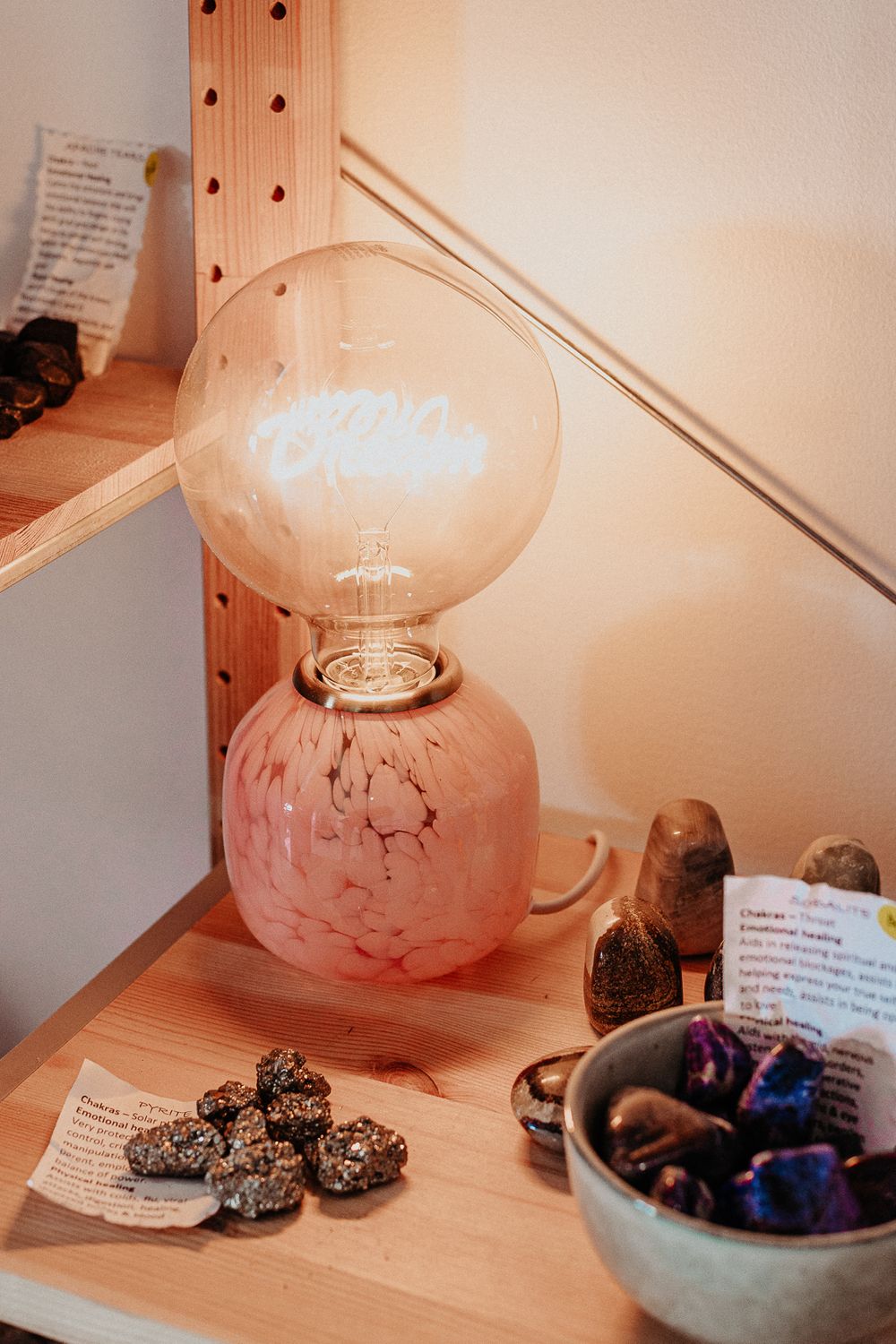 Pink-tinted display of crystals and minerals with descriptive cards under warm lighting.