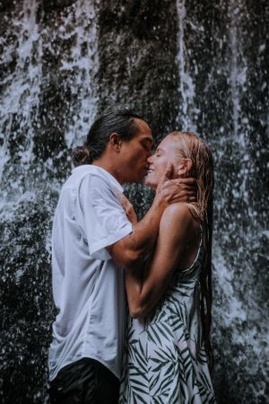 A romantic couple sharing a tender moment in front of a waterfall.
