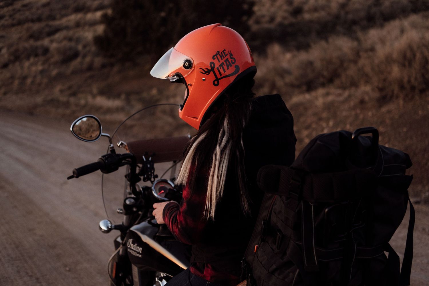 Motorcycles parked on a dusty desert trail with orange safety gear visible.
