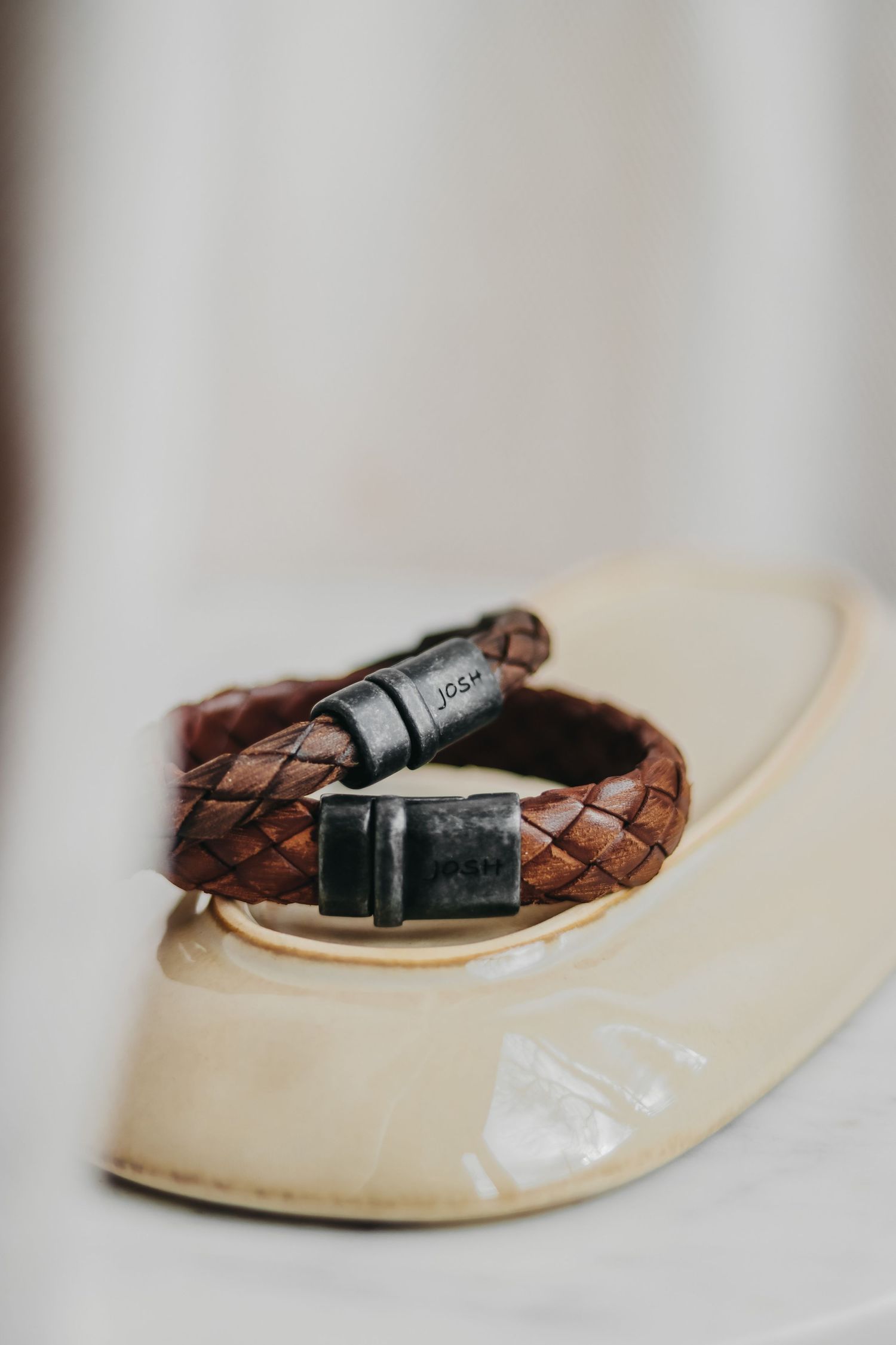 Productfoto van een bruine armband met zwarte sluitingen op een witte achtergrond, geschikt voor sieradenmarketing.