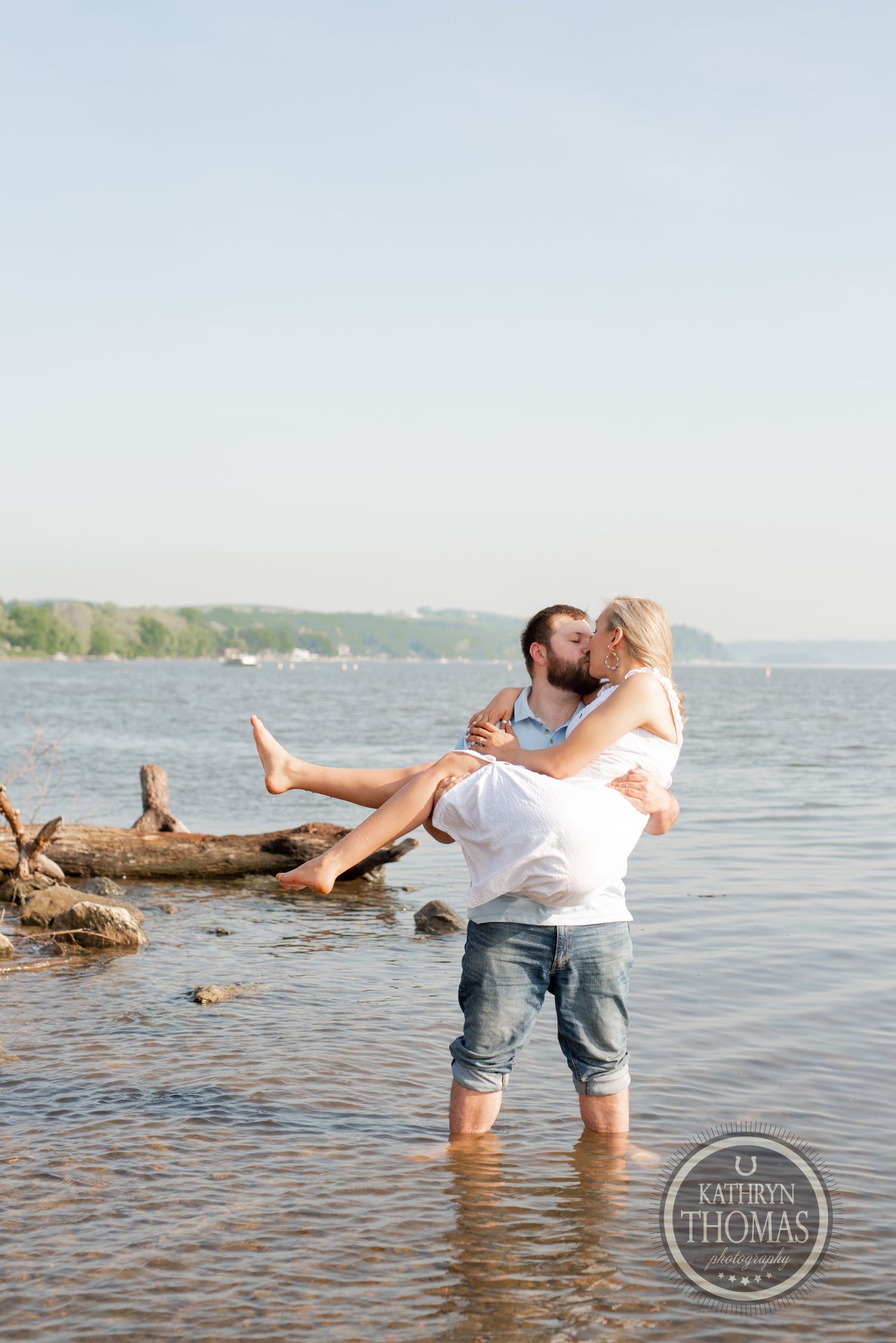 A playful moment captured in the water with driftwood and lake in the background.