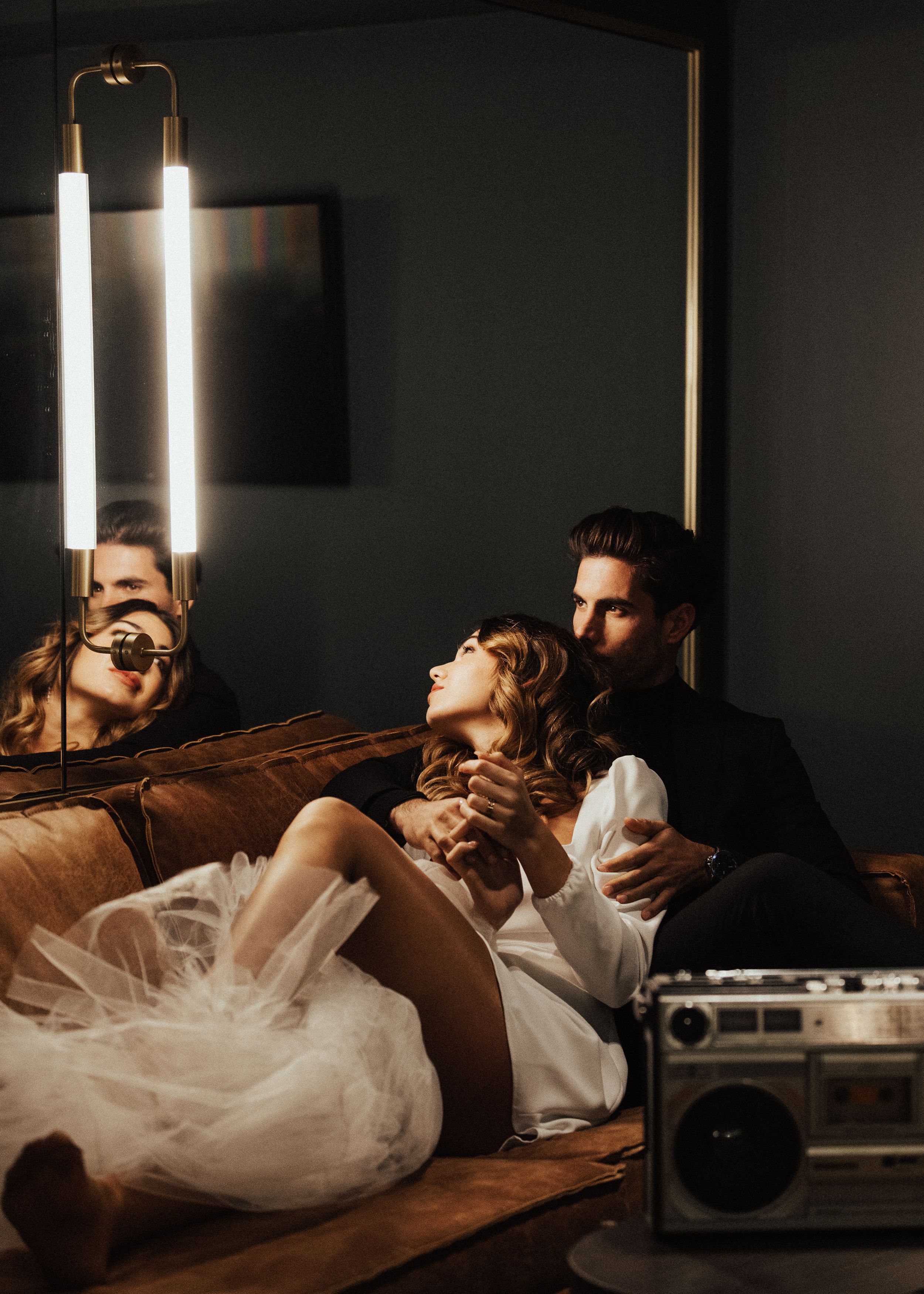 Dramatic wedding portraits with couple reclining near retro boombox with mood lighting.