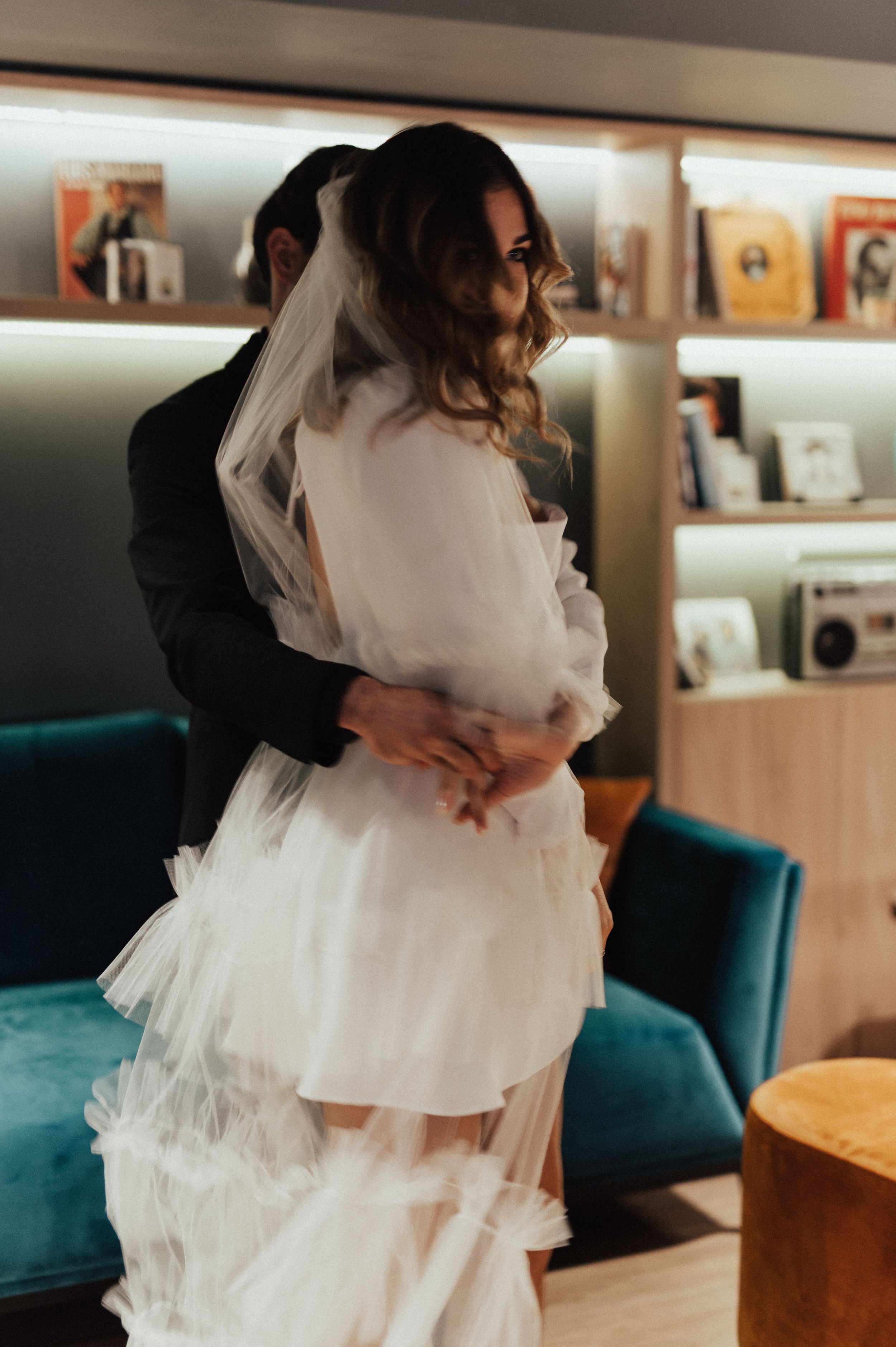 A flowing white tulle dress creates movement against a modern interior backdrop.