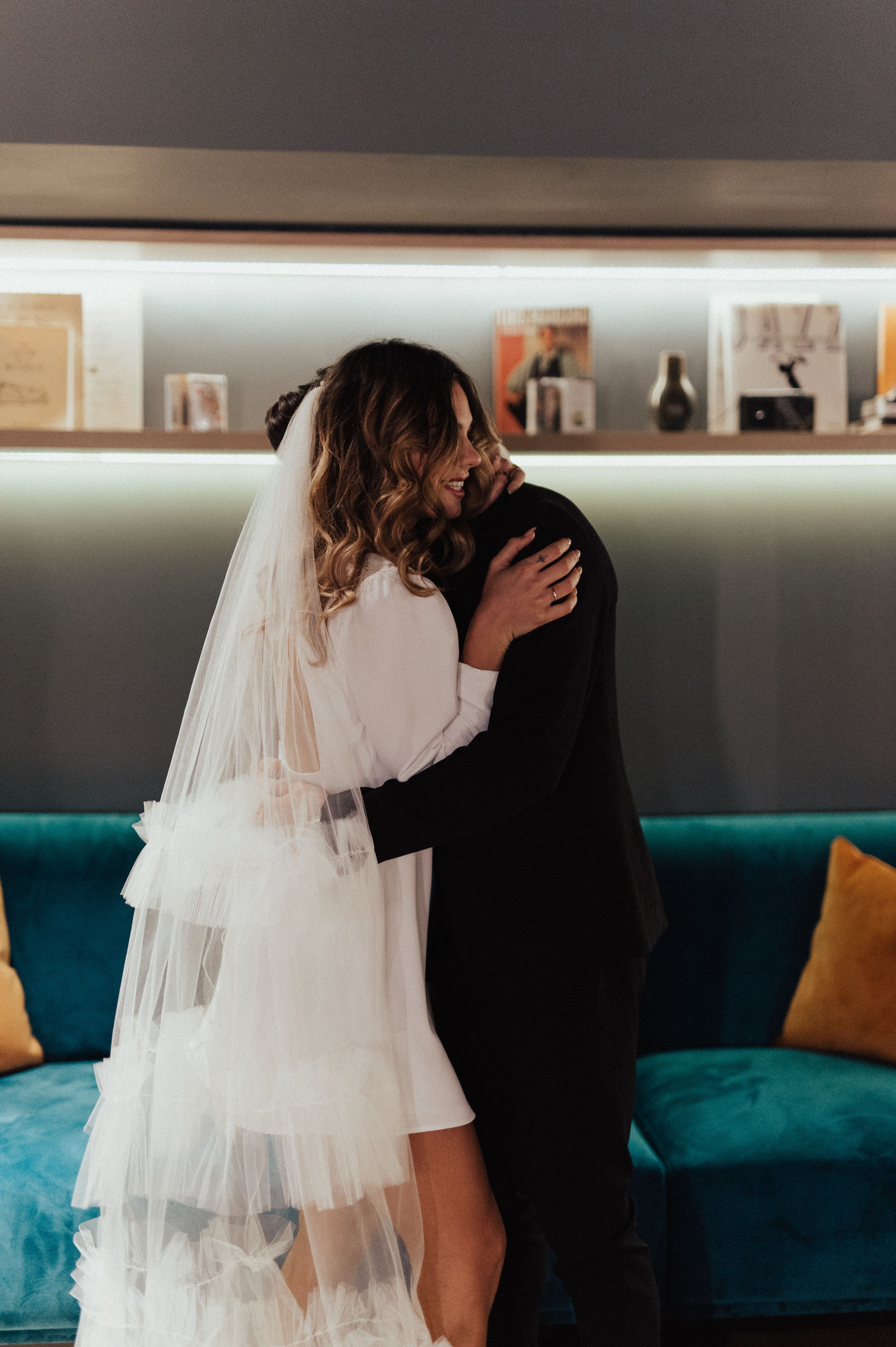 A romantic scene with white tulle and black attire against a teal sofa.