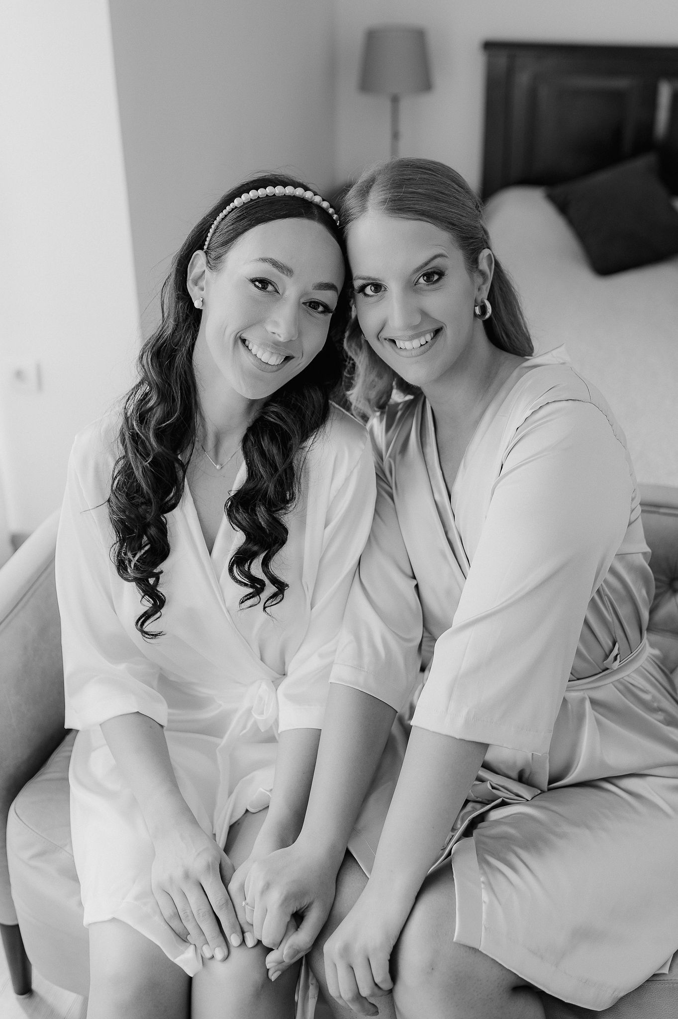 Two friends in robes sharing a joyful moment during wedding preparations.