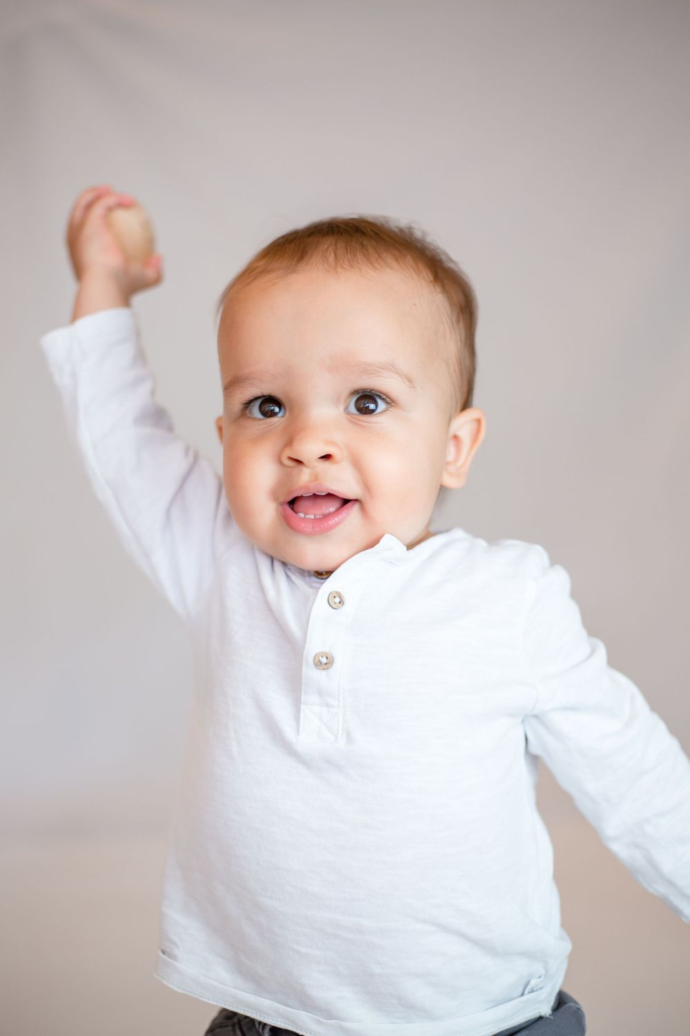professional photo of little boy lifting his arm and smiling