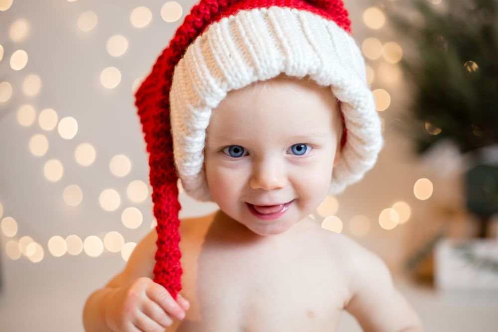 professional photo of girl in santa hat and christmas lights smiling at camera