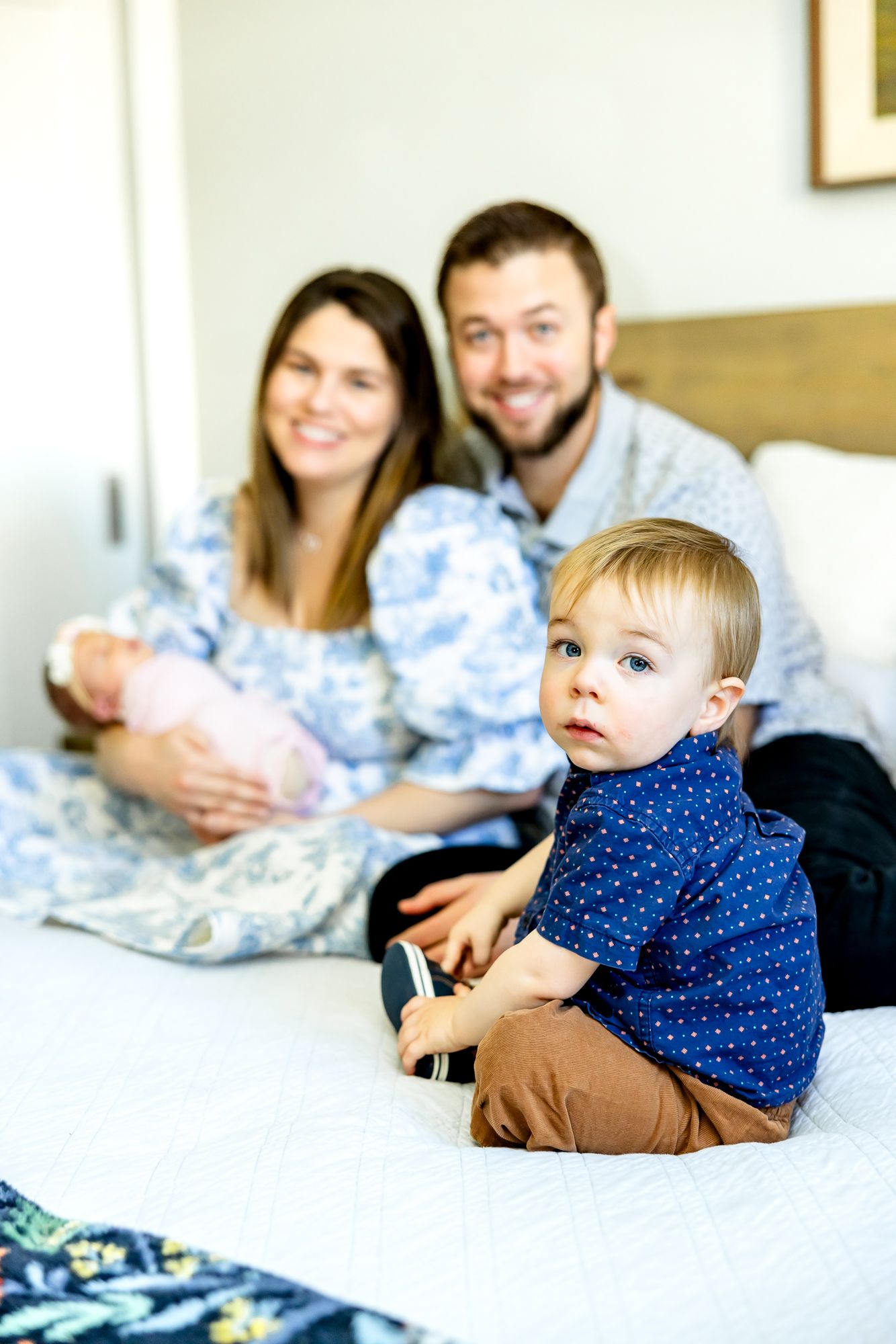 Focus on toddler boy as his parents hold his baby sister in the background during newborn photos in Colorado Springs.