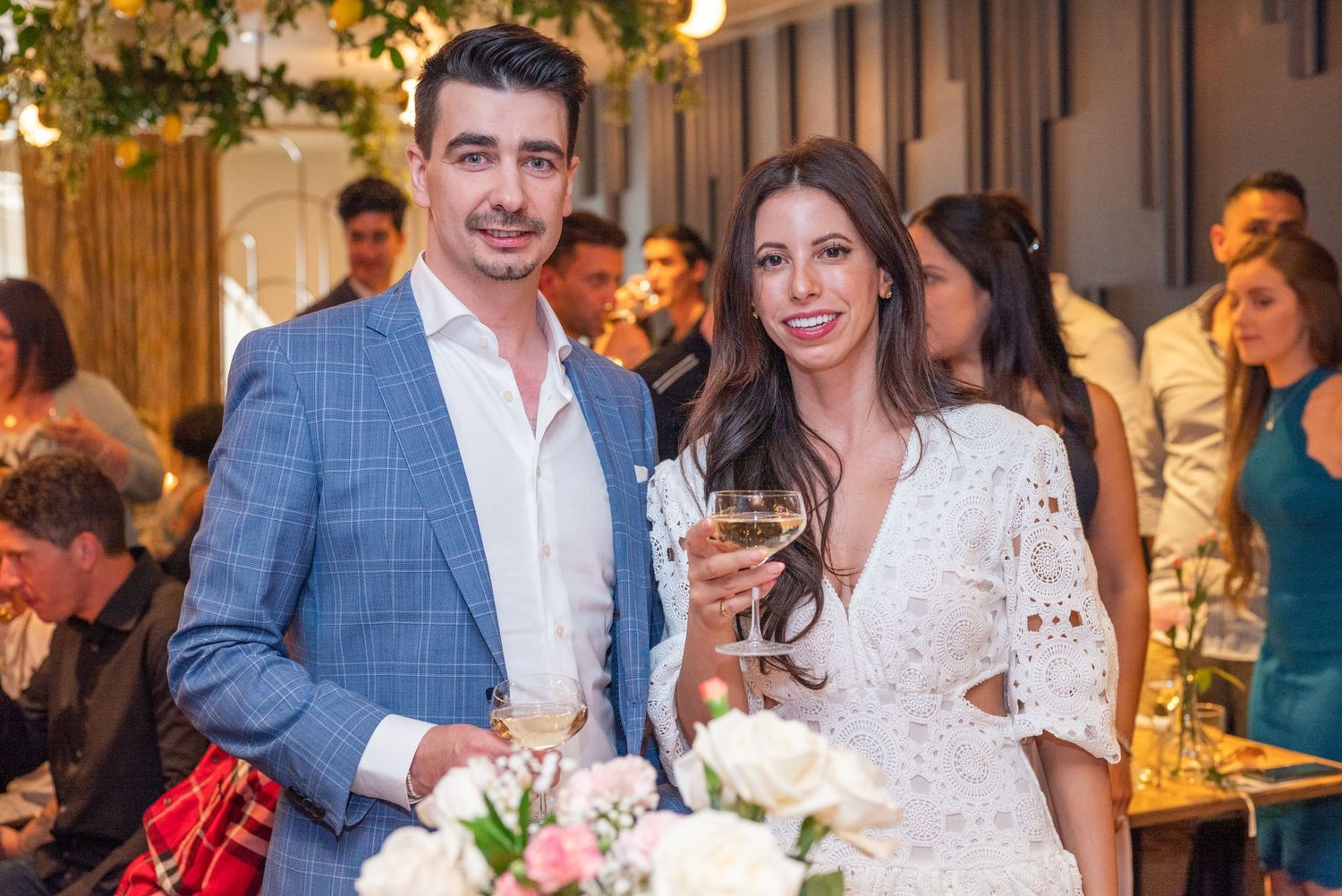 Elegant couple in formal attire celebrate with wine at indoor event.