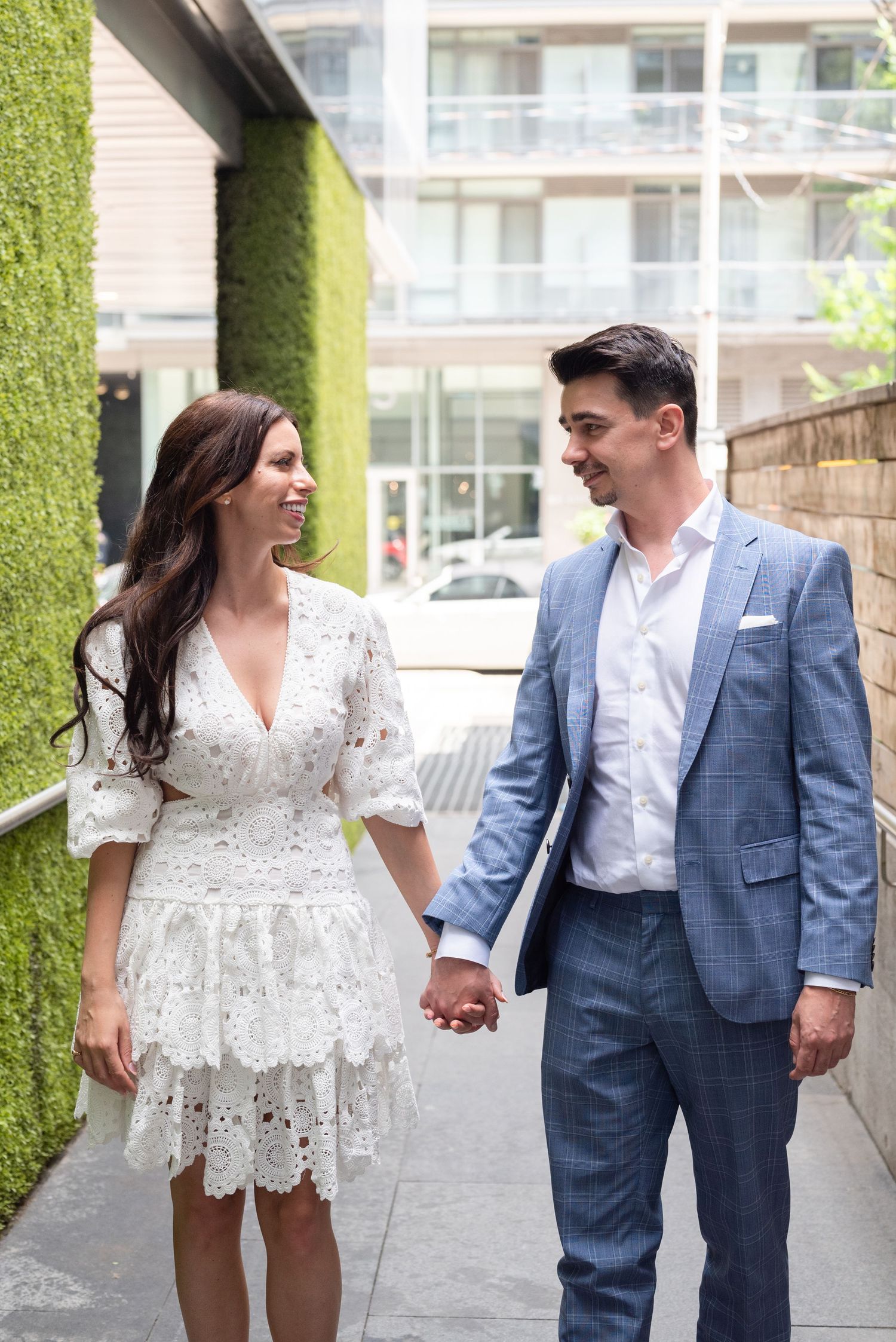 A couple shares a joyful moment while walking together in formal attire.