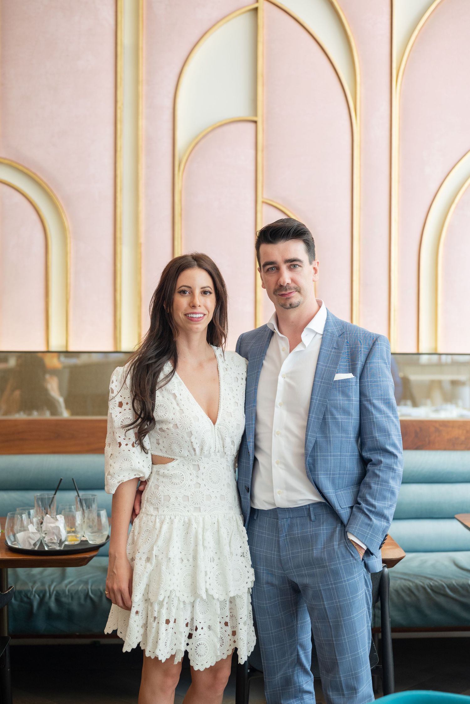 A couple stands together in a chic restaurant interior with art deco design elements.