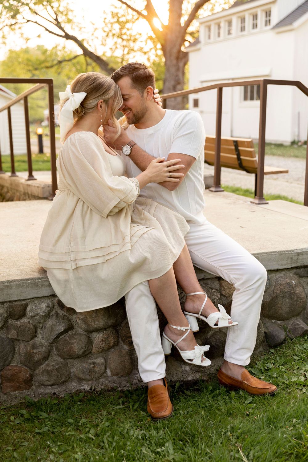 pregnant couple sitting on a porch in front of the white park at cranberry lake park