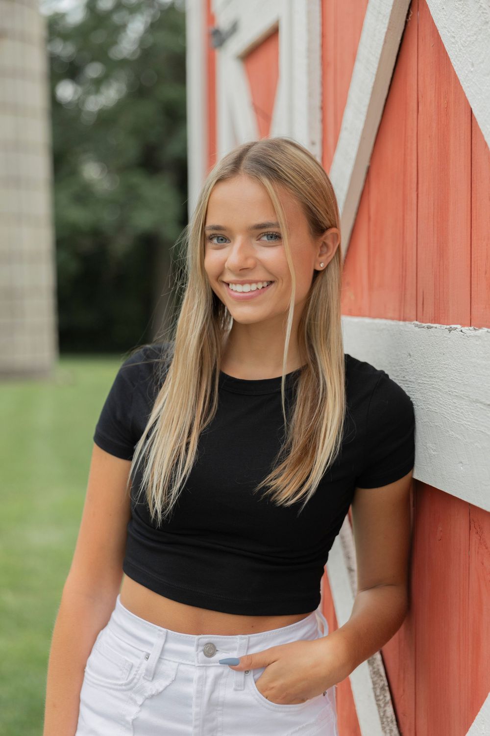 teenage girl leaning on a red barn at cranberry lake park