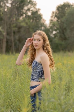 teenage girl pushing her hair behind her ear in a field of grasses at cranberry lake park