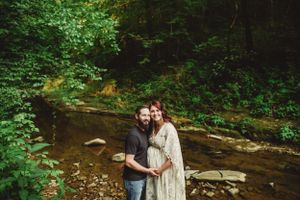 A romantic photoshoot in a lush forest creek setting with natural stone formations and greenery.