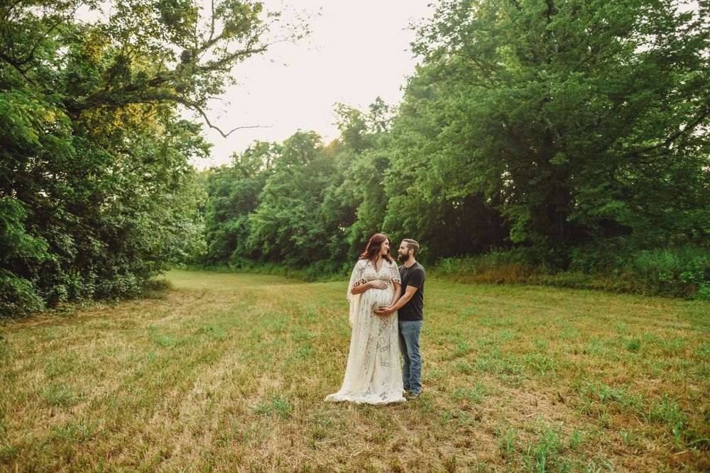A romantic photo session in an open field with tall grass and trees at golden hour.
