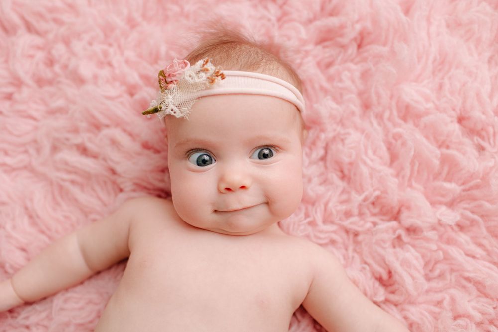 Sweet infant portrait on pink fluffy background wearing dainty floral headband.