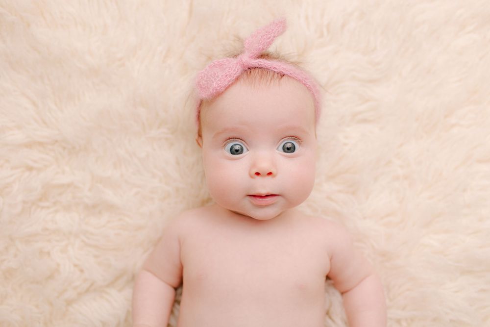 Infant portrait on cream fluffy background with pink knotted headband.