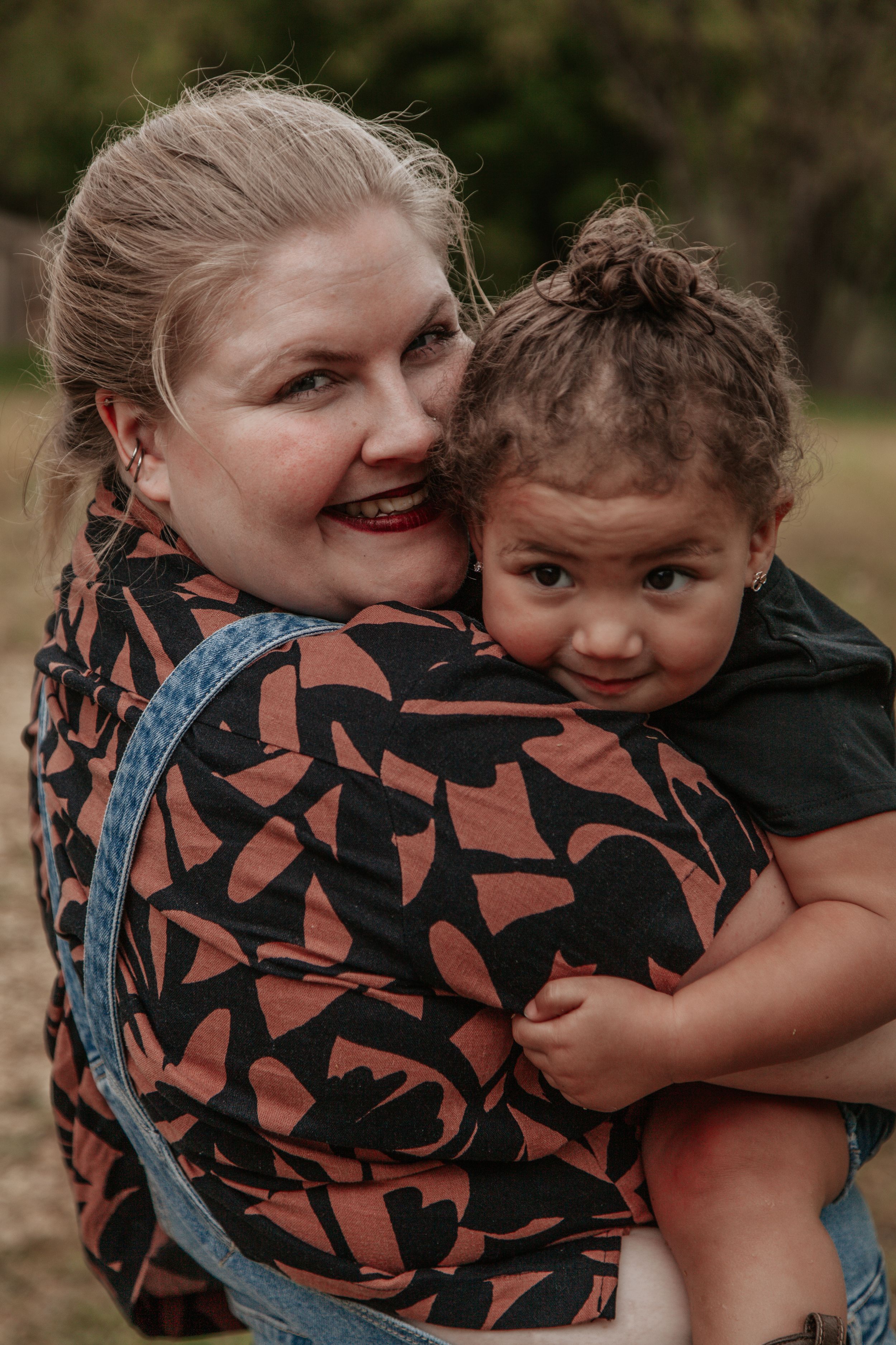 A candid outdoor portrait showing a joyful moment between two people embracing.