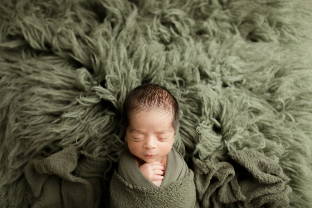 Newborn baby boy on green session setup