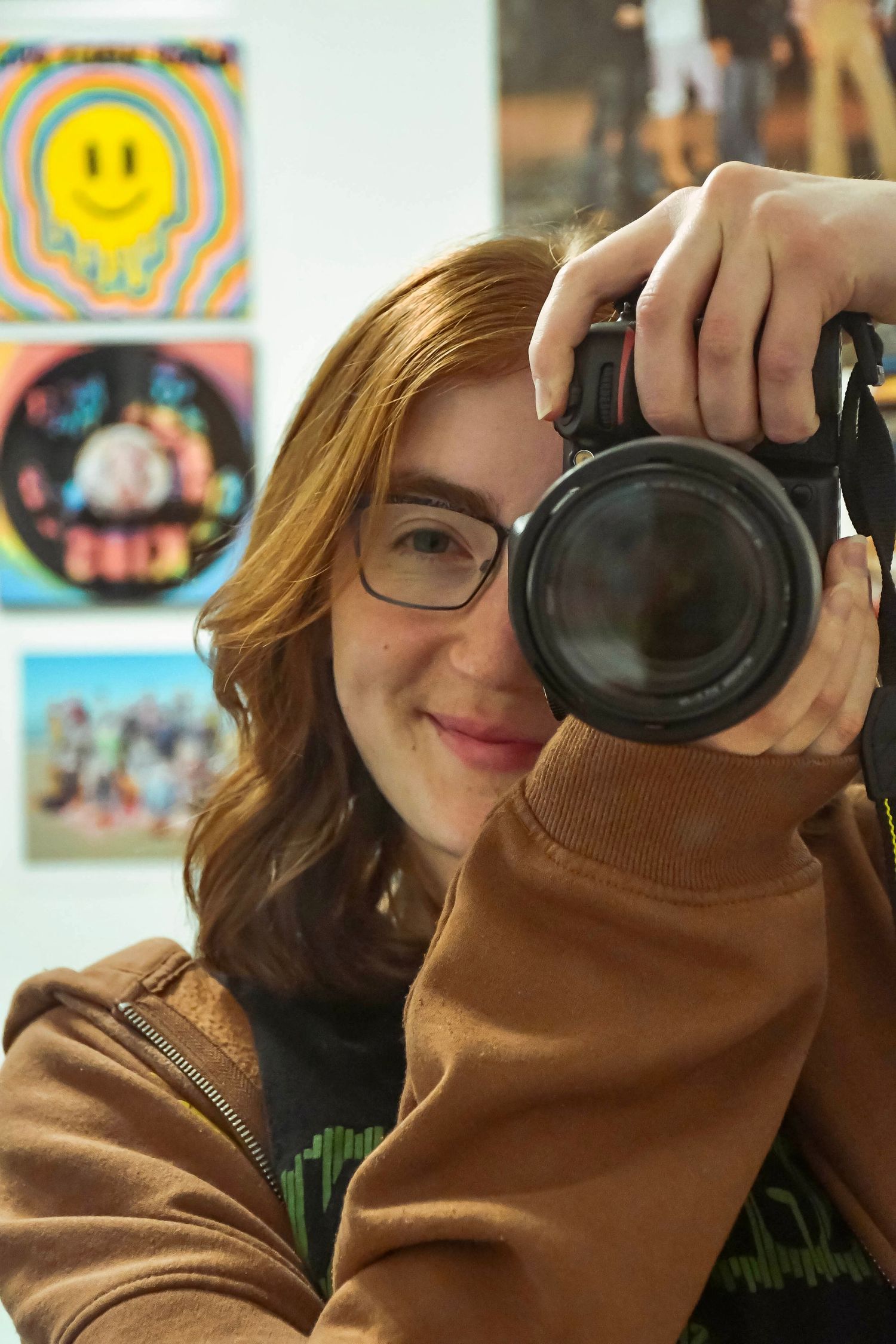 A self portrait taken through a mirror, with posters and artwork in the background. Photo by Jess Daninhirsch.