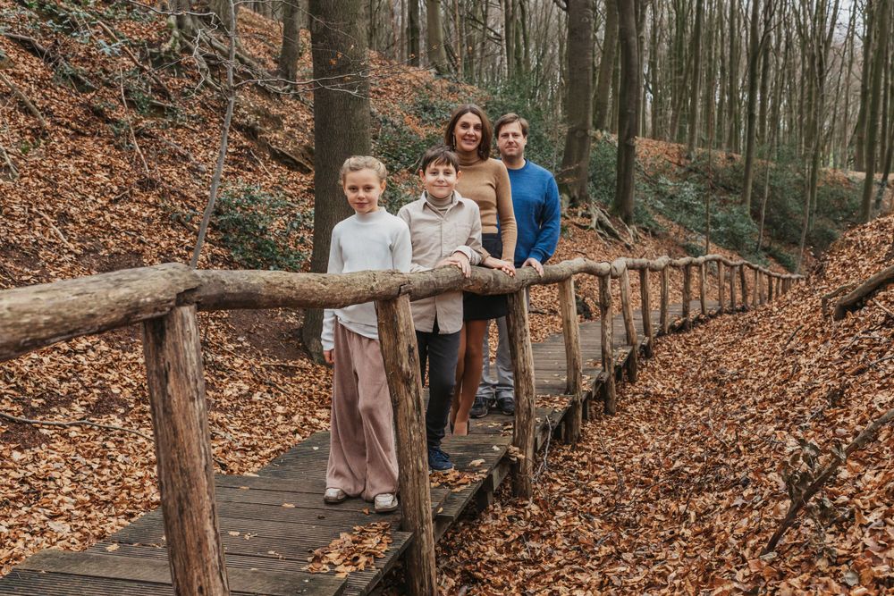 A group stands together on a wooden boardwalk path surrounded by autumn foliage in the forest.